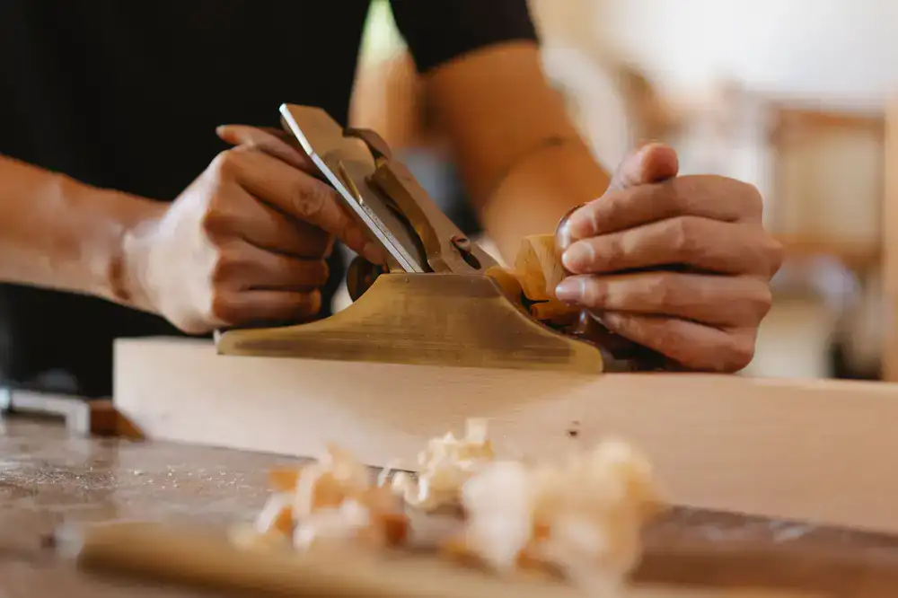 Artisan's hands shaping a custom wooden animal toy at a sunlit workbench