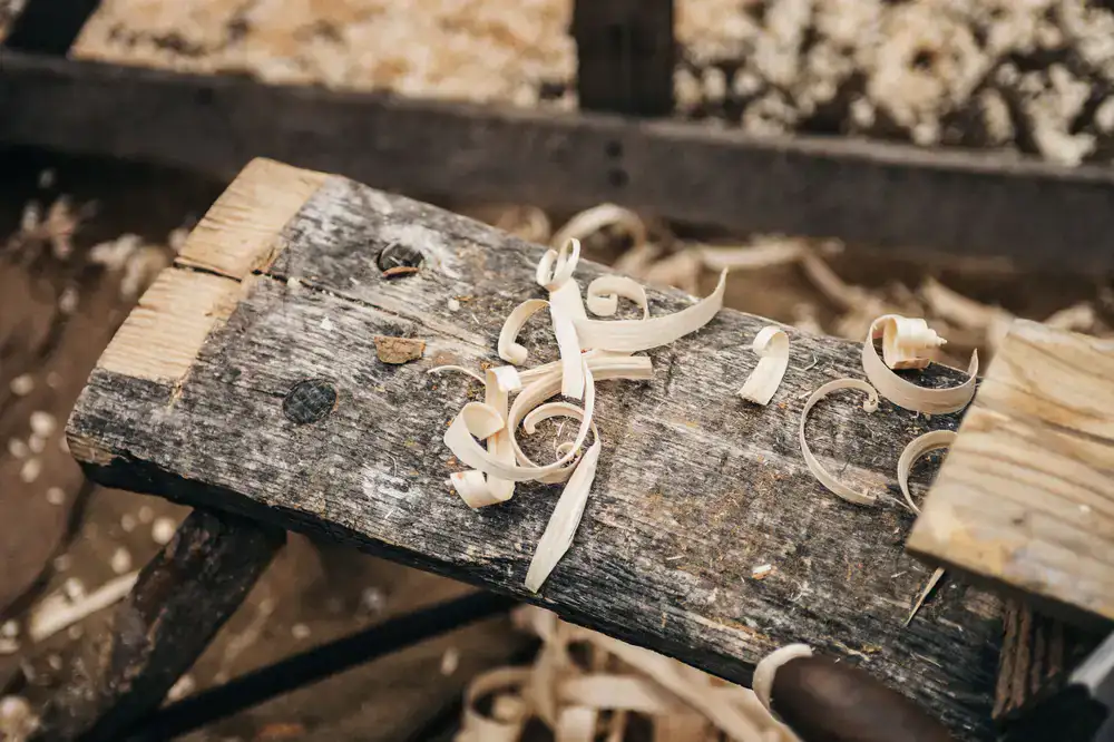 A sunny woodworking bench covered in wood shavings and half-finished wooden toys