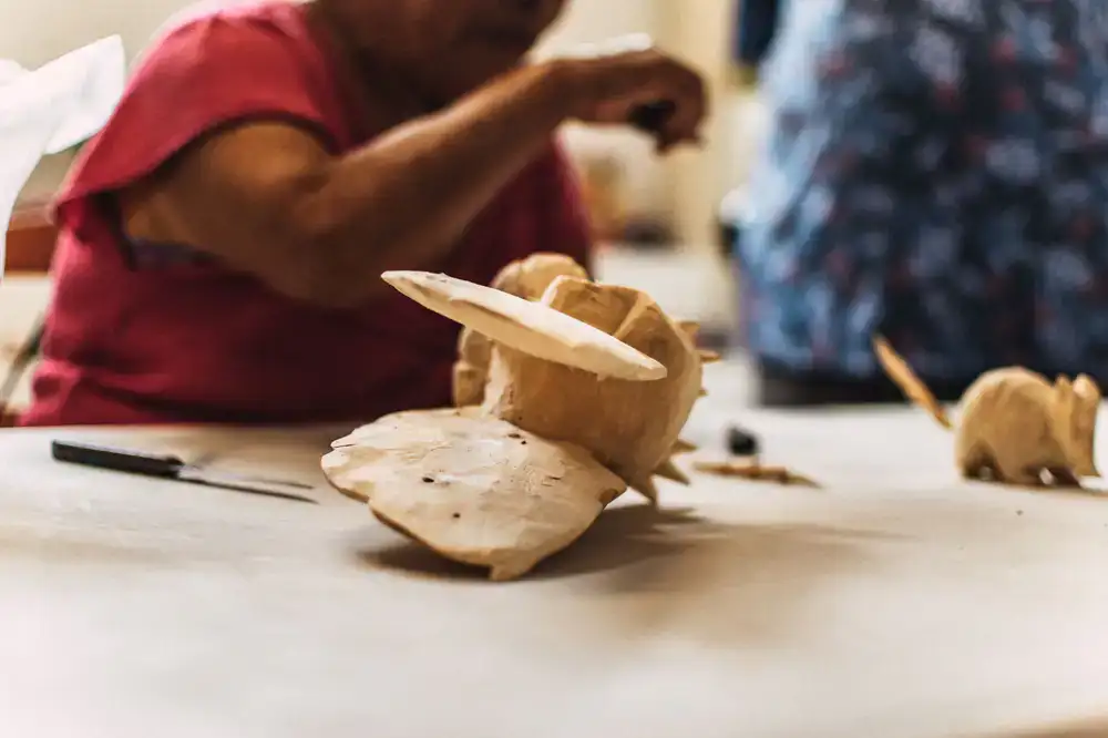 Artisan carving a wooden toy in a sunlit workshop